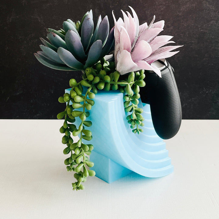 Modern moon 3D printed controller stand holding a generic game controller on desk with faux succulents