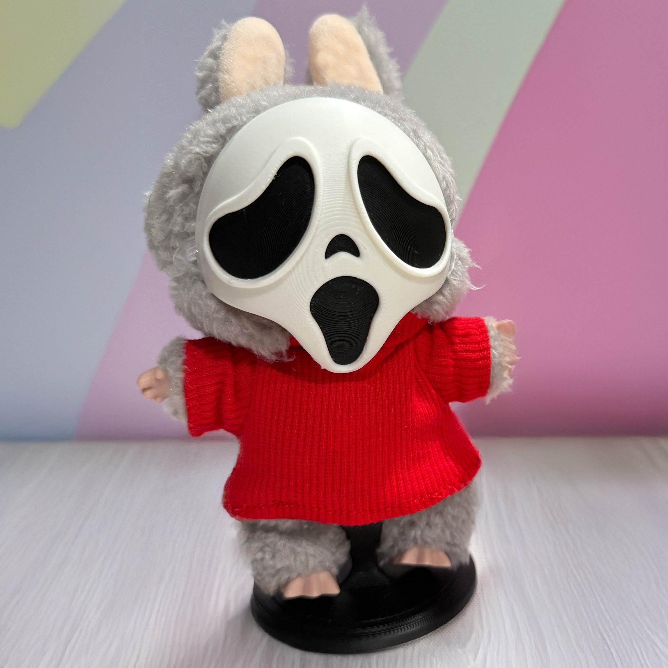 Toy figure with a ghost face mask and red sweater on a colorful background