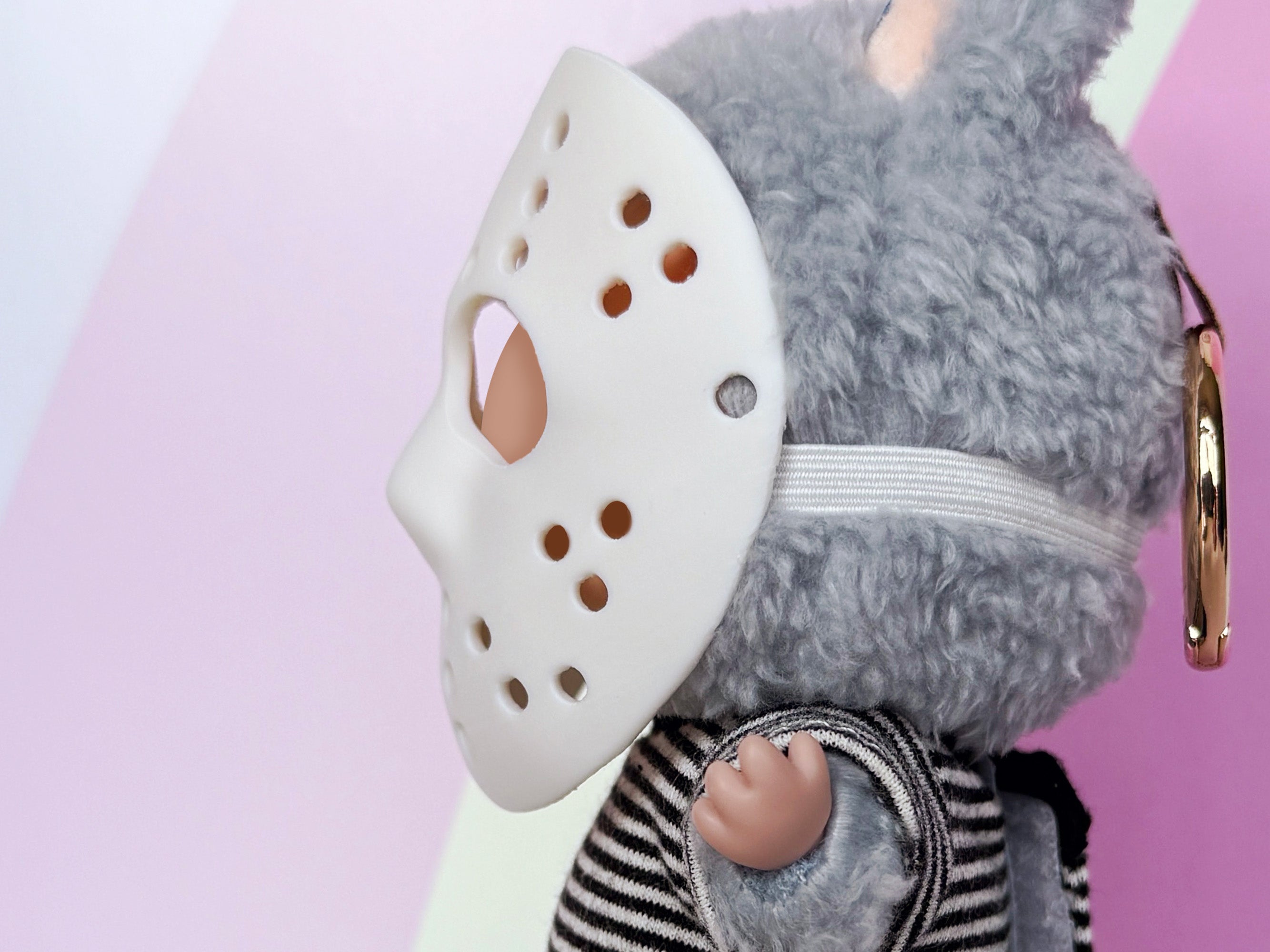 Plush toy with a white mask on a pink background