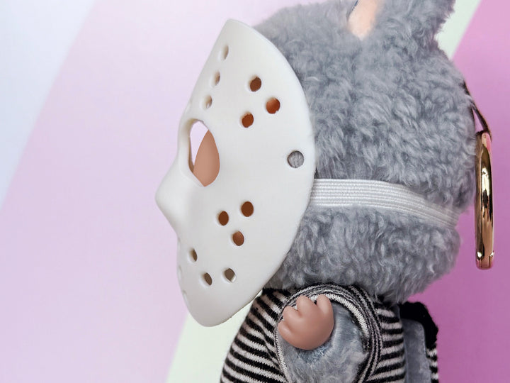Plush toy with a white mask on a pink background