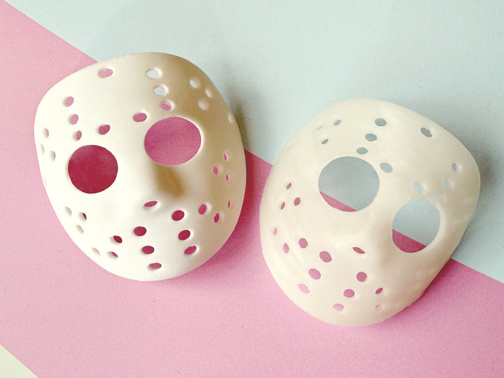Two hockey masks on a pink and gray background