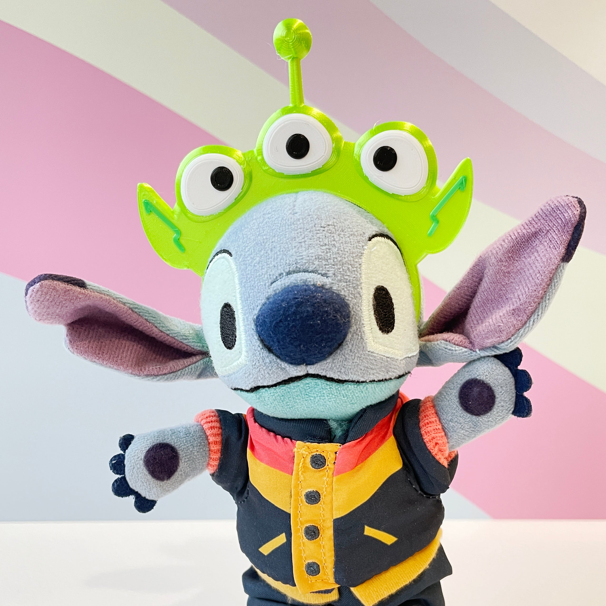 Lime Green Alien Headband with 3 eyes and an antenna on a blue plush on a pastel background