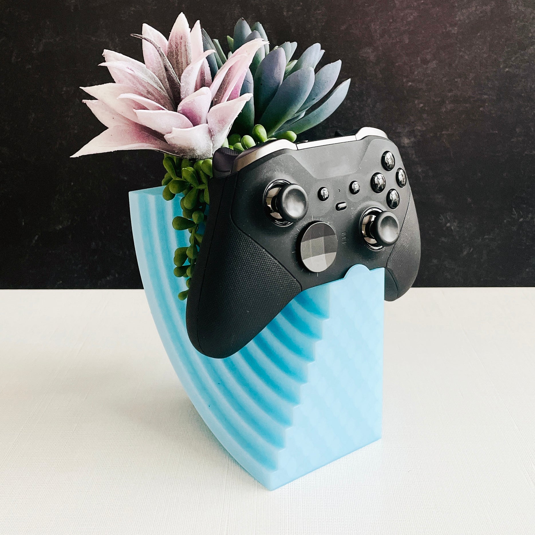 Gaming controller-shaped planter with succulents on a black and white background