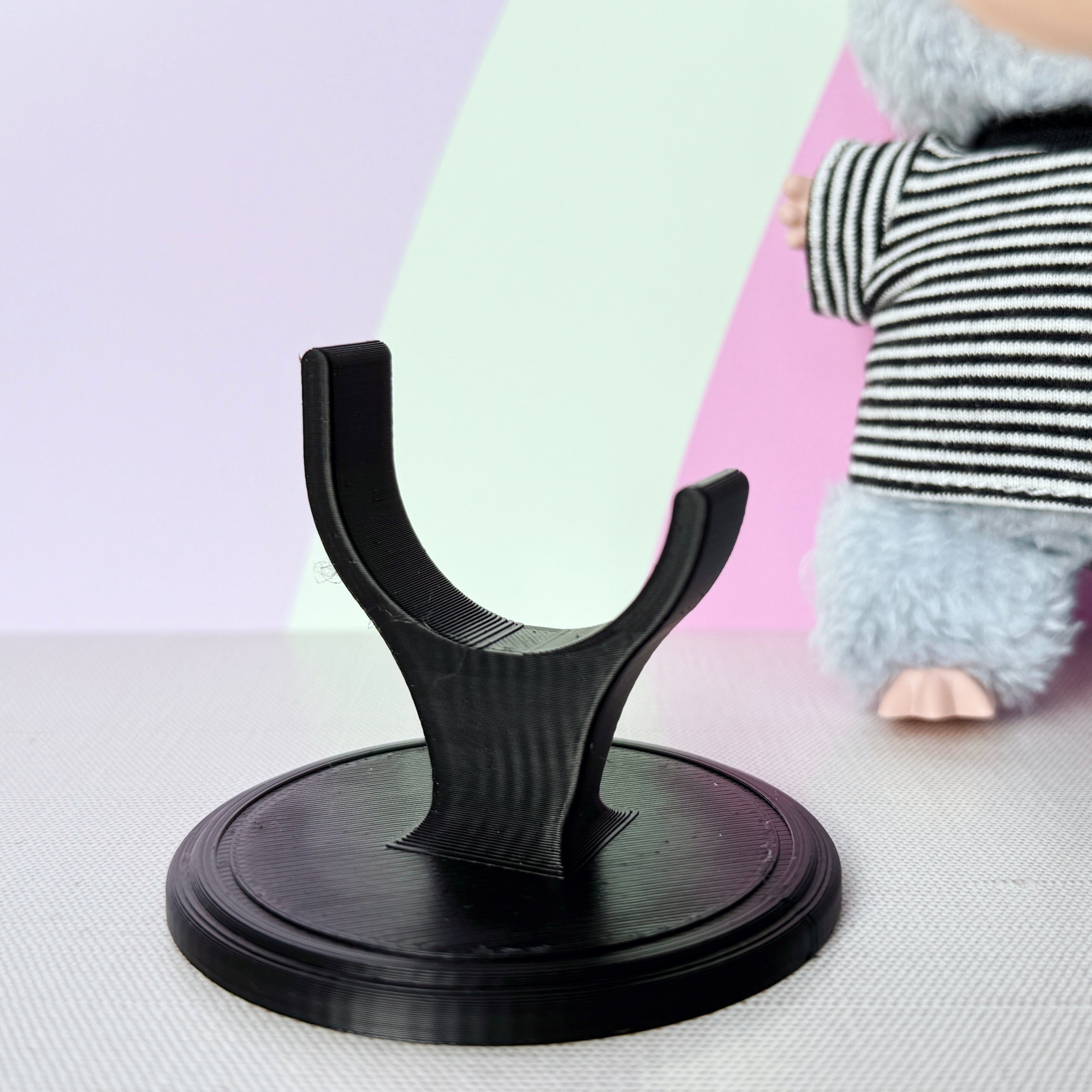 Black stand on a colorful surface with a plush toy in the background