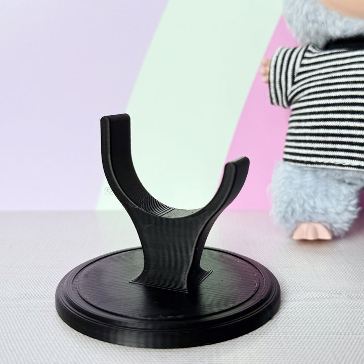 Black stand on a colorful surface with a plush toy in the background