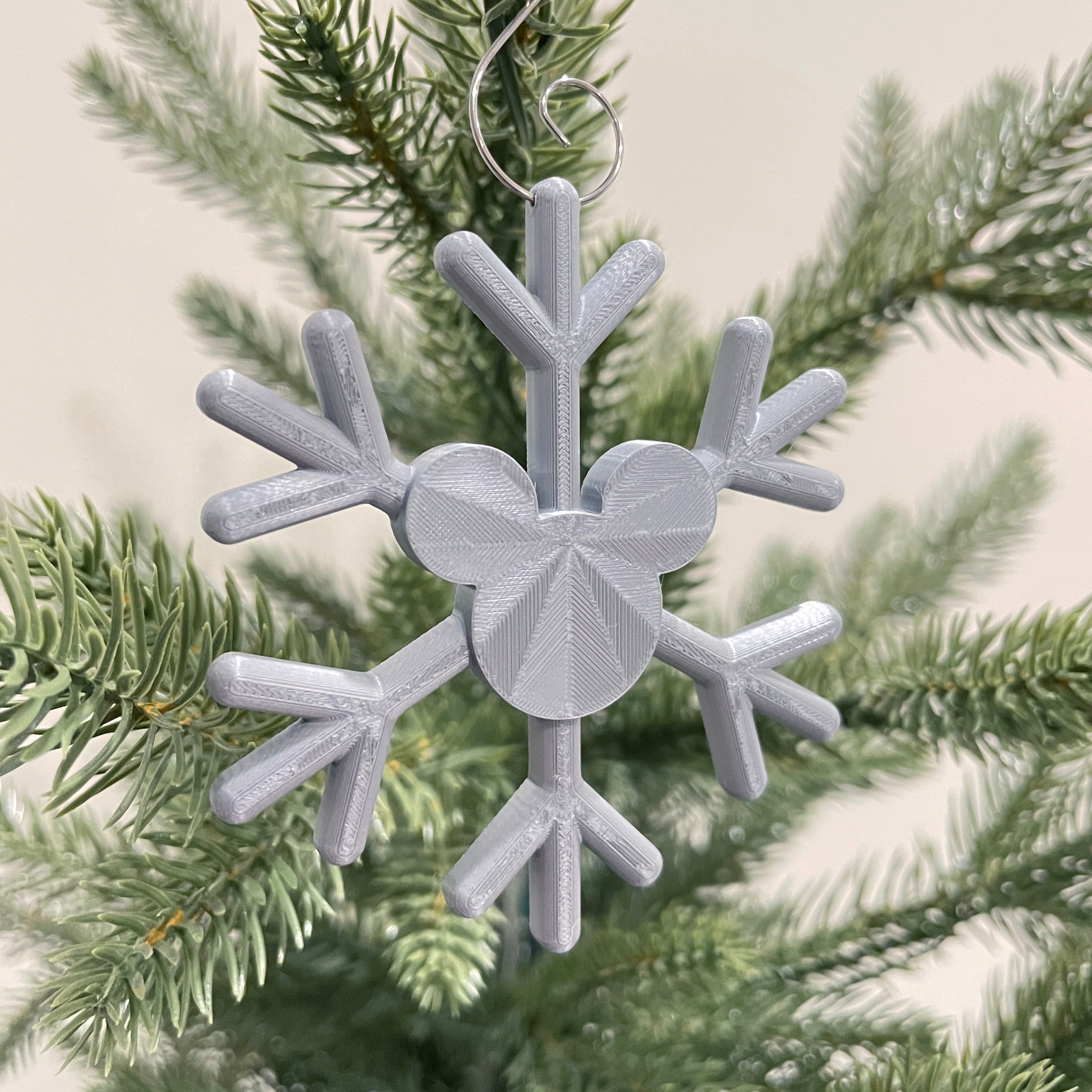 Silver snowflake-shaped ornament with a heart in the center on a Christmas tree.