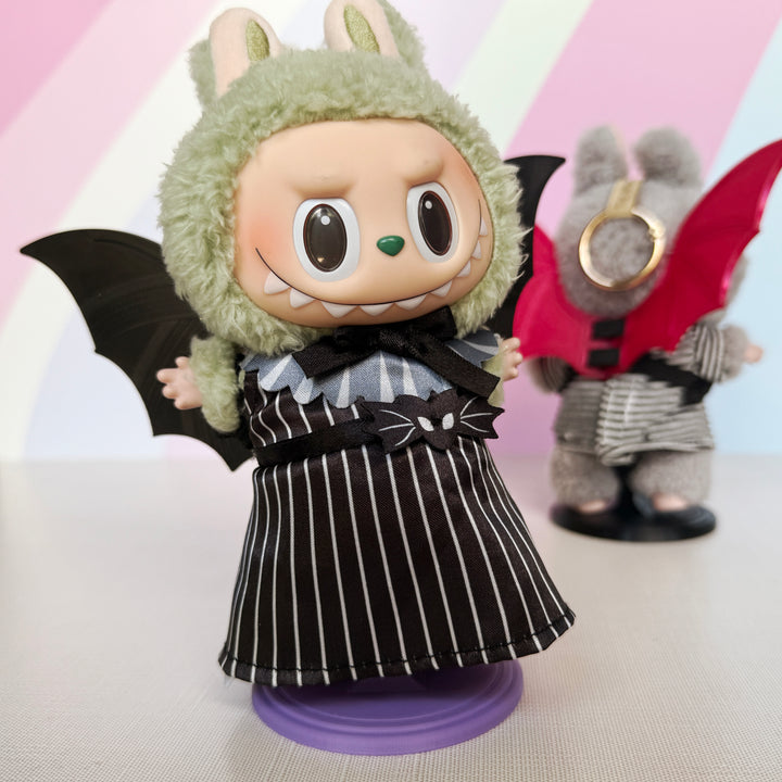 Plush toys with black and red bat wings and green furry head on a white background