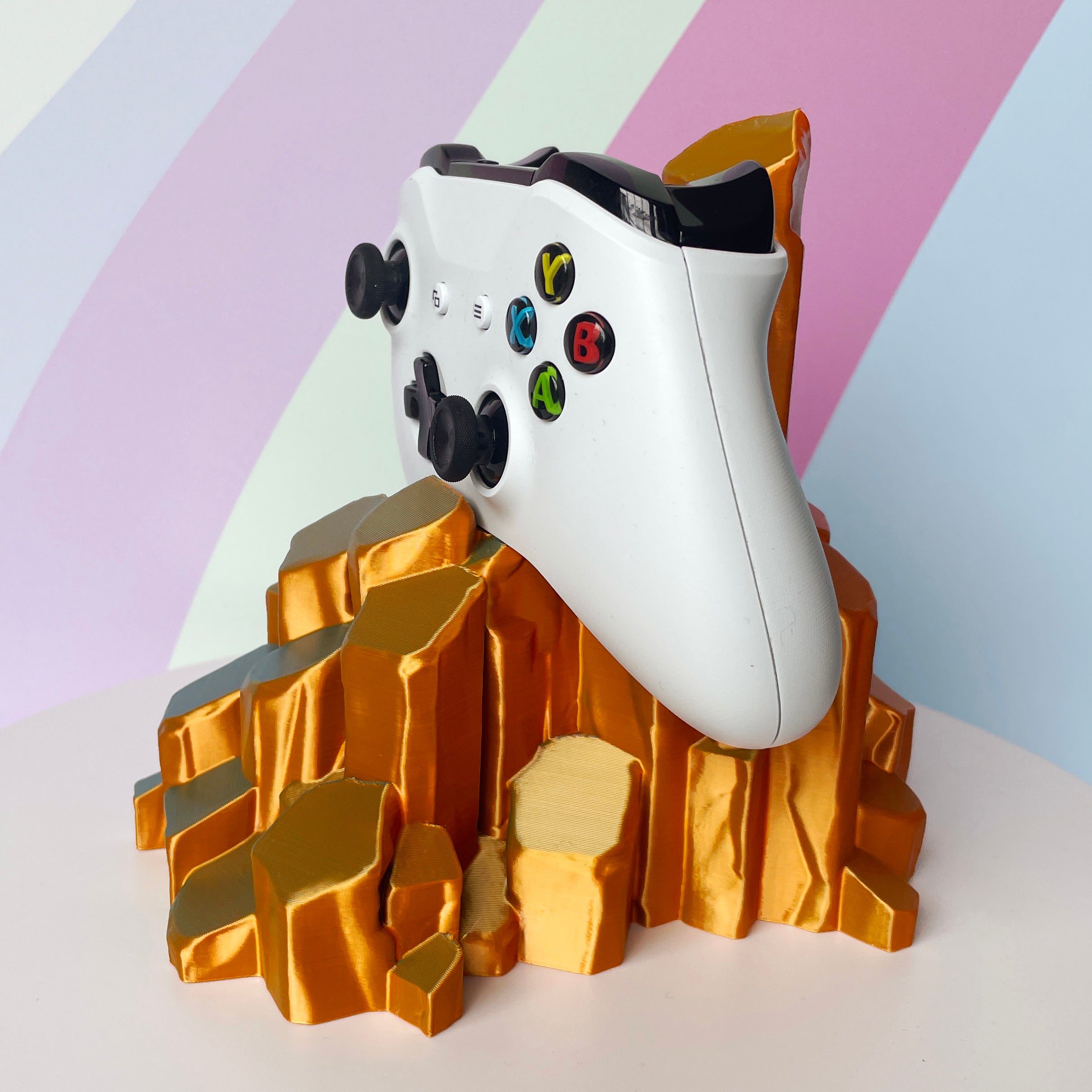 White gaming controller on sun-kissed quartz 3D printed controller stand on white background against a colorful background