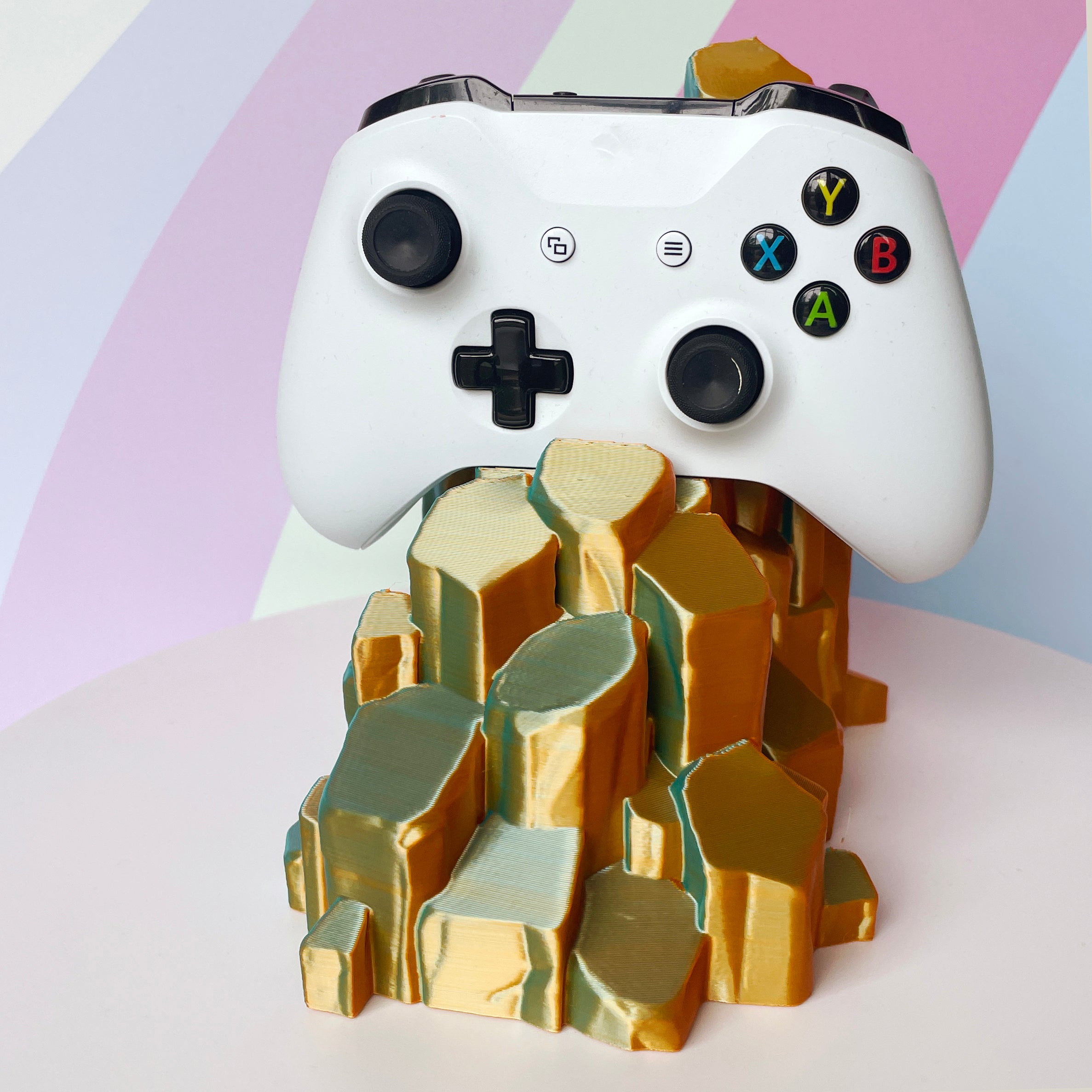 White gaming controller on sun-kissed quartz 3D printed controller stand on white background against a colorful background