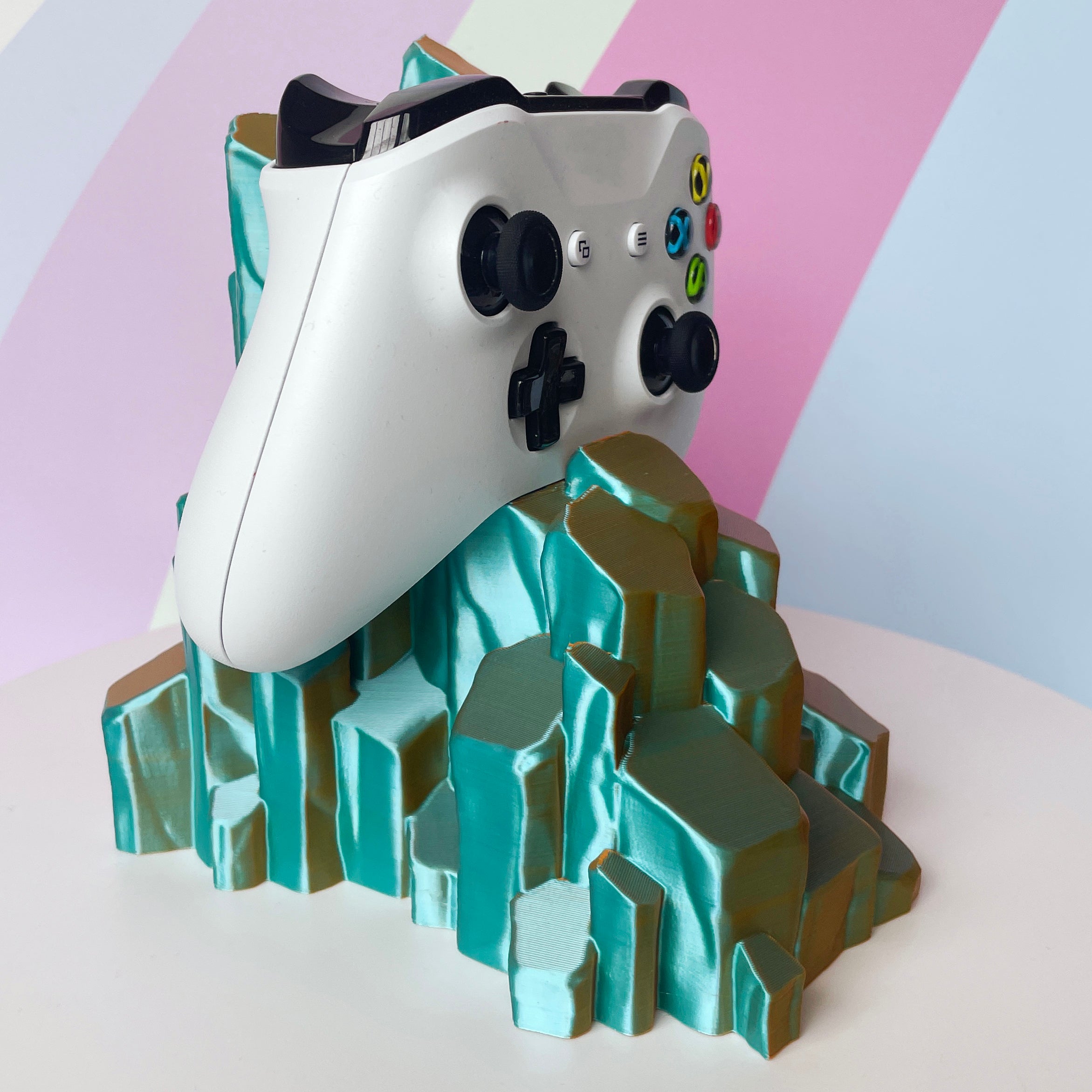 White gaming controller on sun-kissed quartz 3D printed controller stand on white background against a colorful background