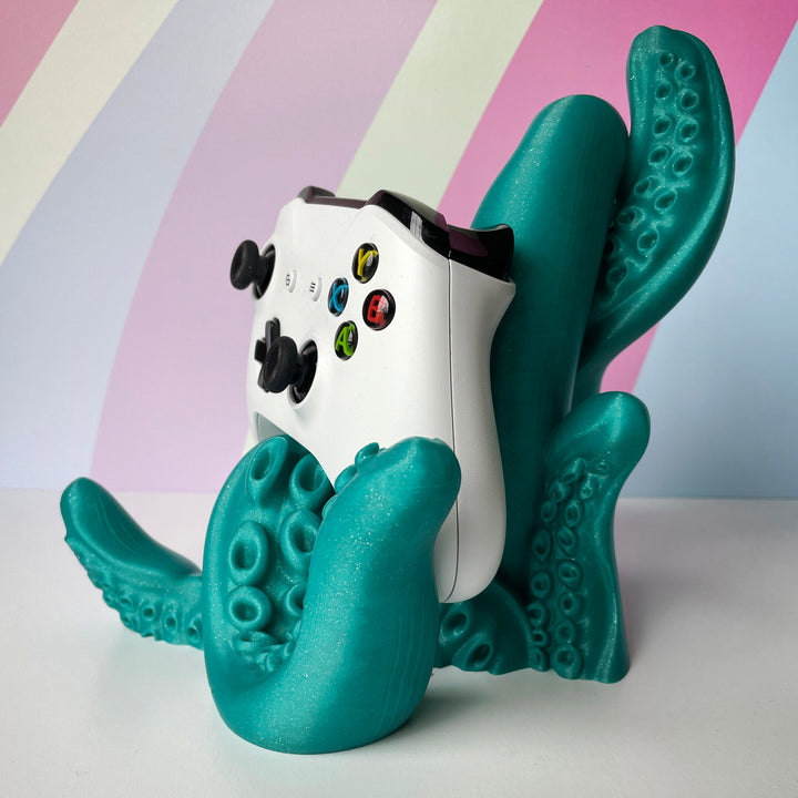 White gaming controller held by a teal octopus-like stand against a colorful background