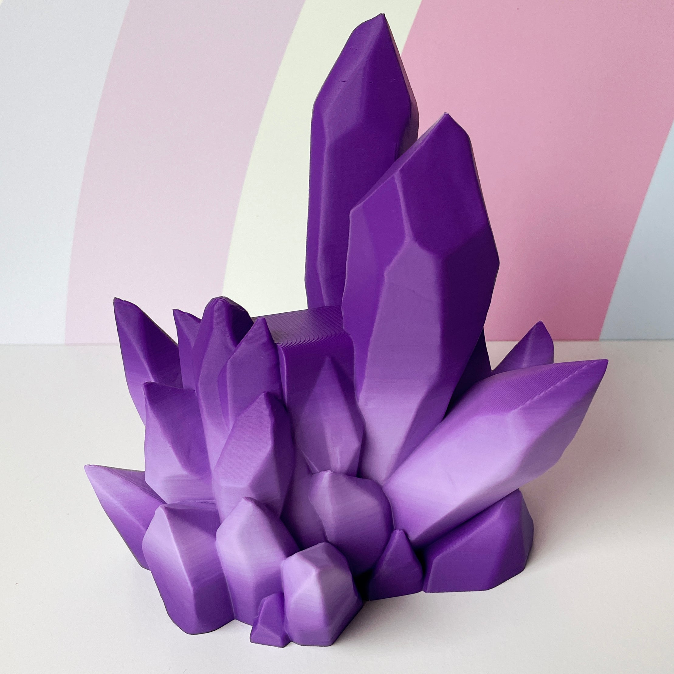Purple-ombre 3D printed crystal-style controller stand on white surface with a pink and white abstract background