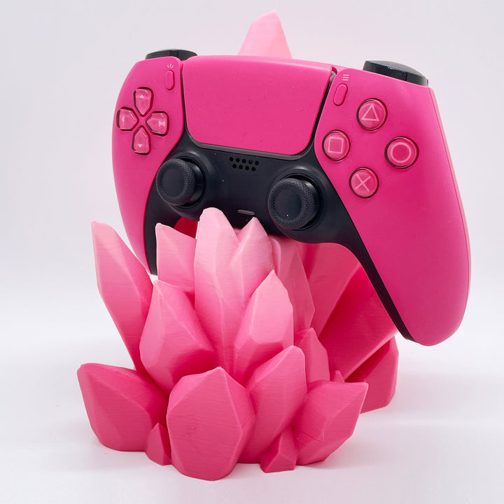 Pink gaming controller on a pink crystal-like stand against a white background